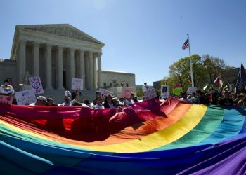 Demonstrators stand in front of a rainbow flag of the Supreme Court in Washington, Tuesday, April 28, 2015. The Supreme Court is set to hear historic arguments in cases that could make same-sex marriage the law of the land. The justices are meeting Tuesday to offer the first public indication of where they stand in the dispute over whether states can continue defining marriage as the union of a man and a woman, or whether the Constitution gives gay and lesbian couples the right to marry. (AP Photo/Jose Luis Magana)