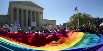 Demonstrators stand in front of a rainbow flag of the Supreme Court in Washington, Tuesday, April 28, 2015. The Supreme Court is set to hear historic arguments in cases that could make same-sex marriage the law of the land. The justices are meeting Tuesday to offer the first public indication of where they stand in the dispute over whether states can continue defining marriage as the union of a man and a woman, or whether the Constitution gives gay and lesbian couples the right to marry. (AP Photo/Jose Luis Magana)