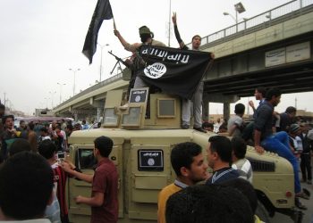 FILE - In this March 20, 2014 file photo, Al-Qaida fighters wave al-Qaida flags as they patrol in a commandeered Iraqi military vehicle in Fallujah, Iraq. Is there a plan B for Iraq? The fall of Ramadi shows the Iraqi army is still weak, Sunni-Shiite reconciliation is slow and U.S. bombing is not decisively helping. (AP Photo, File)