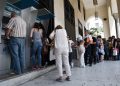 People line up at ATMs outside a National bank branch in the northern Greek port city of Thessaloniki, Monday, June 29, 2015.  Anxious Greeks lined up at ATMs as they gradually began dispensing cash again on the first day of capital controls imposed in a dramatic twist in Greece’s five-year financial saga. Banks will remain shut until next Monday, and a daily limit of 60 euros ($67) has been placed on cash withdrawals from ATMs . (AP Photo/Giannis Papanikos)