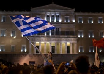 A supporter of the No vote waves a Greek flag in front of the parliament after the results of the referendum at Syntagma square in Athens, Sunday, July 5, 2015. Greeks overwhelmingly rejected creditors' demands for more austerity in return for rescue loans in a critical referendum Sunday, backing Prime Minister Alexis Tsipras, who insisted the vote would give him a stronger hand to reach a better deal. (AP Photo/Emilio Morenatti)