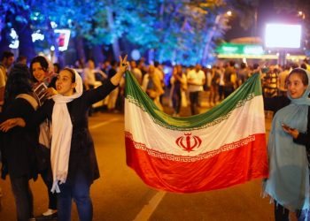 epa04846971 Iranians hold the Iran's national flags as they celebrate in the street of Tehran, Iran, 14 July 2015, after nuclear talks between Iran and World powers ended in Vienna, Austria. Iran and six world powers have agreed on a deal over Iran's controversial nuclear programme. Iranians were so happy by hearing that world powers are ready to lift the sanctions against the country.  EPA/ABEDIN TAHERKENAREH