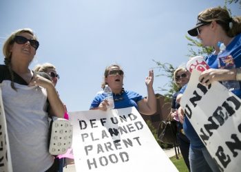 Mary Daley, center, speaks with fellow Catholic protesters during an anti-abortion rally outside of Planned Parenthood in Fort Worth, Texas, on Tuesday, July 28, 2015. (Laura Buckman /Star-Telegram via AP)  MAGS OUT; (FORT WORTH WEEKLY, 360 WEST); INTERNET OUT; MANDATORY CREDIT