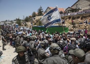 Israeli settlers watch the demolition of a building at the Jewish settlement of Beit El, near the West Bank town of Ramallah, Wednesday, July 29, 2015. Israeli bulldozers began demolishing a contested housing complex in a West Bank settlement on Wednesday as the prime ministerís office announced the ìimmediate constructionî of some 300 new units at another location in the same settlement and advanced plans for about 500 new units in east Jerusalem.  (AP Photo/Tsafrir Abayov)