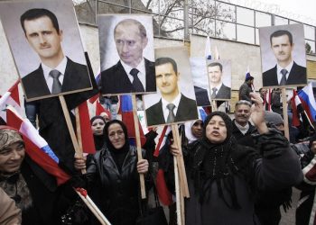FILE - In this Sunday, March 4, 2012 file photo, Syrians hold posters of Syrian President Bashar Assad, far left, and Russian President Vladimir Putin, second left, during a pro-Syrian goverment protest in front of the Russian Embassy in Damascus, Syria. In ramping up its military involvement in Syria's civil war, Russia appears to be betting that the West, horrified by Islamic State's atrocities, may be willing to tolerate Assad for a while, perhaps as part of a transition. (AP Photo/Muzaffar Salman, File)