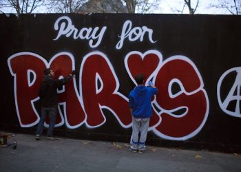 Two men paint a mural reads: "Pray for Paris" in tribute to the victims of the Paris attacks, in Paris, Saturday Nov. 14, 2015. French President Francois Hollande vowed to attack Islamic State without mercy as the jihadist group admitted responsibility Saturday for orchestrating the deadliest attacks inflicted on France since World War II. (AP Photo/Thibault Camus)