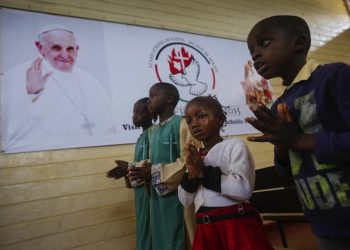 epa05026463 Kenyan children pray in front of a banner welcoming Pope Francis at St. Joseph the Worker Catholic Church, where Pope is scheduled to visit during his stay, in Nairobi's Kangemi neighborhood in Kenya, 15 November 2015. Kenya is preparing for the upcoming papal visit in late November, his first stop on a three-nation Africa tour.  EPA/DAI KUROKAWA