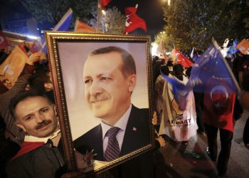 A supporter of the Justice and Development Party, (AKP), holds a picture of Turkey's President Recep Tayyip Erdogan as people celebrate outside the AKP headquarters, in Istanbul, late Sunday, Nov. 1, 2015. Turkey's ruling party secured a stunning victory in Sunday's snap parliamentary election, sweeping back into single-party rule only five months after losing it. The preliminary result, reported after nearly 99 percent of votes were counted, would show the ruling Justice and Development party (AKP) had won more than 49 percent of the vote and was projected to get 316 seats in parliament, in a stunning victory.(AP Photo/Emrah Gurel)