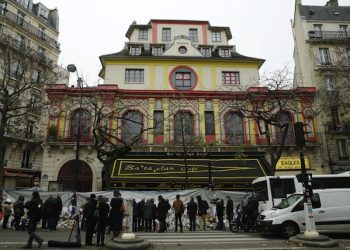 epa05044407 People pay their respect in front of the Bataclan concert place during the national memorial service to pay homage to the victims of the November 13 terrorist attacks, in Paris, France, 27 November 2015. 130 people were killed and hundreds injured in the terror attacks which targeted the Bataclan concert hall, the Stade de France national sports stadium, and several restaurants and bars in the French capital on 13 November 2015.  EPA/YOAN VALAT