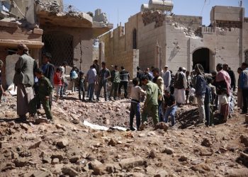 People stand around a crater made by a Saudi-led coalition airstrike in Sanaa, Yemen, Sunday, Nov. 29, 2015. (AP Photo/Hani Mohammed)