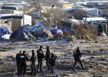 French riot police officers walk in the Calais migrant camp, northern France Thursday, Jan.21, 2016. Bulldozers moved in this week to clean the terrain after hundreds of migrants began moving deeper into the squalid camp. Some fear the camp will eventually be razed to rid Calais of migrants. (AP Photo/Michel Spingler)
