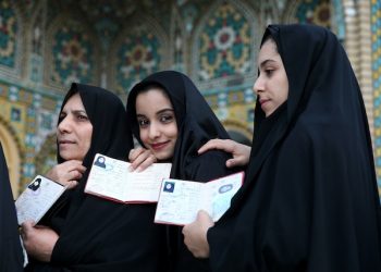 Iranian women show their identification, as they queue in a polling station to vote for the parliamentary and Experts Assembly elections in Qom, 125 kilometers (78 miles) south of the capital Tehran, Iran, Friday, Feb. 26, 2016. Iranians across the Islamic Republic voted Friday in the country's first election since its landmark nuclear deal with world powers, deciding whether to further empower its moderate president or side with hard-liners long suspicious of the West. The election for Iran's parliament and a clerical body known as the Assembly of Experts hinges on both the policies of President Hassan Rouhani, as well as Iranians worries about the country's economy, long battered by international sanctions. (AP Photo/Ebrahim Noroozi)