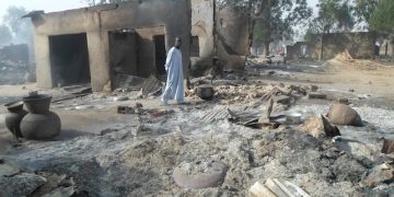 A man walks past burnt out houses following an attack by Boko Haram in Dalori village 5 kilometers (3 miles) from Maiduguri, Nigeria, Sunday Jan. 31, 2016. A survivor hidden in a tree says he watched Boko Haram extremists firebomb huts and listened to the screams of children among people burned to death in the latest attack by Nigeriaí s homegrown Islamic extremists. (AP Photo/Jossy Ola)