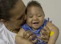 Caio Julio Vasconcelos who was born with microcephaly is kissed by a therapist at the Institute for the Blind in Joao Pessoa, Brazil, Thursday, Feb. 25, 2016. Researchers from the Centers of Disease Control and Prevention continue to fan out across one of Brazil's poorest states in search of mothers and infants for a study aimed at determining whether the Zika virus is causing babies to be born with unusually small heads. (AP Photo/Andre Penner)