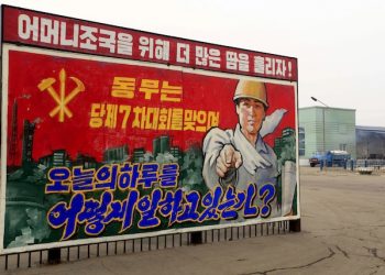 In this Sunday, March 13, 2016 photo, a truck loaded with bags of fertilizer leaves the Hungnam Fertilizer Complex behind a propaganda billboard that reads: "How are you spending today on the occasion of the party's 7th conference?" in Hungnam, South Hamgyong Province, North Korea. North Koreans are being mobilized en masse to boost production and demonstrate their loyalty to leader Kim Jong Un in a 70-day campaign aimed at wiping out "indolence and slackness." Bright red flags and propaganda posters have gone up around the country to emphasize the importance of meeting or exceeding production targets. (AP Photo/Kim Kwang Hyon)