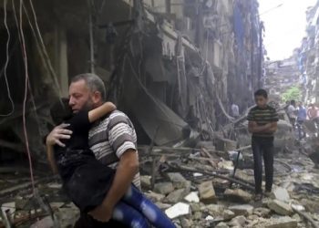In this image made from video and posted online from Validated UGC, a man carries a child after airstrikes hit Aleppo, Syria, Thursday, April 28, 2016. A Syrian monitoring group and a first-responders team say new airstrikes on the rebel-held part of the contested city of Aleppo have killed over a dozen people and brought down at least one residential building. The new violence on Thursday brings the death toll in the past 24-hours in the deeply divided city to at least 61 killed. (Validated UGC via AP video)