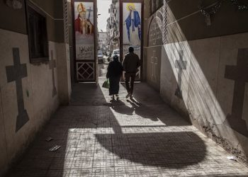 FILE - In this Tuesday, Jan. 6, 2015 file photo, Coptic Christians walk outside St. Markos Church in Minya, south of Cairo. Egypt's president has vowed that those responsible for stripping an elderly Christian woman and parading her naked on the streets will be brought to justice. The May 20 attack in the village of Karma in Minya province, south of Cairo, followed a rumor that the woman's son had an affair with a Muslim woman. (AP Photo/Roger Anis, File)