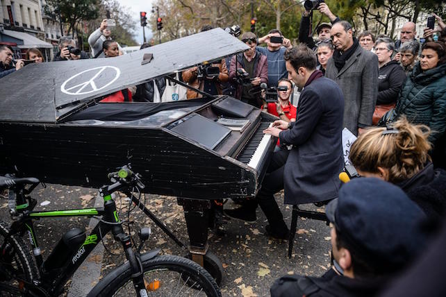 epa05028435 Pianist Davide Martello plays the  Lennon's song Imagine in front of the memorial set near the Bataclan concert venue in Paris, France, 16 November 2015. More than 130 people were killed and hundreds injured in the terror attacks which targeted the Bataclan concert hall, the Stade de France national sports stadium, and several restaurants and bars in the French capital on 13 November. Authorities believe that three coordinated teams of terrorists armed with rifles and explosive vests carried out the attacks, which the Islamic State (IS) extremist group has claimed responsibility for.  EPA/CHRISTOPHE PETIT TESSON