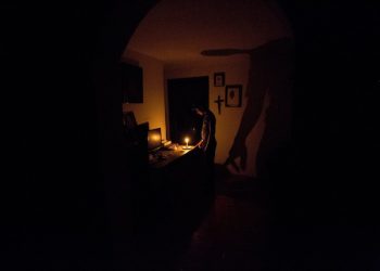 In this Saturday, April 23, 2016 photo, a boy illuminates his home with a candle during a 24-hour blackout, in the El Calvario neighborhood of El Hatillo, just outside of Caracas, Venezuela. Energy rationing has been added to the hardships faced by Venezuelans overwhelmed by inflation, shortages of food and medicine and rising crime. (AP Photo/Fernando Llano)