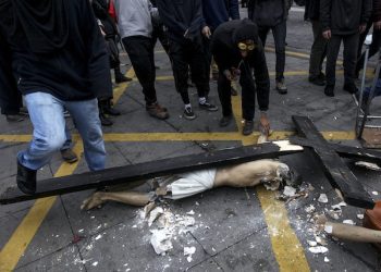 A crucified Christ lies on a street destroyed after a group of hooded vandals carried it out of a church that they looted in the Chilean capital in Santiago, Chile, Thursday, June 9, 2016.(AP Photo/Felix Marquez)