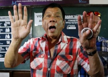 Front-running presidential candidate Mayor Rodrigo Duterte gestures at photographers to move back prior to voting in a polling precinct at Daniel R. Aguinaldo National High School at Matina district, his hometown in Davao city in southern Philippines Monday, May 9, 2016. Duterte was the last to vote among five presidential hopefuls. (AP Photo/Bullit Marquez)