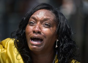 Annette Stubbs, a pastor at a local church, prays for victims a few blocks from a crime scene at the nightclub where a mass shooting took place the night before in Orlando, Fla., Sunday, June 12, 2016. A gunman opened fire inside the gay nightclub early Sunday, killing at least 50 people before dying in a gunfight with SWAT officers, police said. (Loren Elliott/Tampa Bay Times via AP)