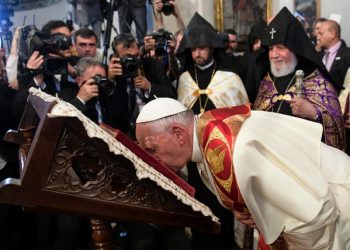 Pope Francis flanked by Catholicos Karekin II, right, kisses a Holy Book as he visits the Apostolic Cathedral of Etchmiadzin, Yerevan, Armenia, Friday, June 24, 2016. Pope Francis is in Armenia for a three-day visit. (L'Osservatore Romano/Pool Via AP)