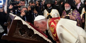 Pope Francis flanked by Catholicos Karekin II, right, kisses a Holy Book as he visits the Apostolic Cathedral of Etchmiadzin, Yerevan, Armenia, Friday, June 24, 2016. Pope Francis is in Armenia for a three-day visit. (L'Osservatore Romano/Pool Via AP)