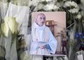 A picture of late Father Jacques Hamel is placed on flowers at the makeshift memorial in front of the city hall closed to the church where an hostage taking left a priest dead the day before in Saint-Etienne-du-Rouvray, Normandy, France, Wednesday, July 27, 2016. The Islamic State group crossed a new threshold Tuesday in its war against the West, as two of its followers targeted a church in Normandy, slitting the throat of an elderly priest celebrating Mass and using hostages as human shields before being shot by police. (AP Photo/Francois Mori)