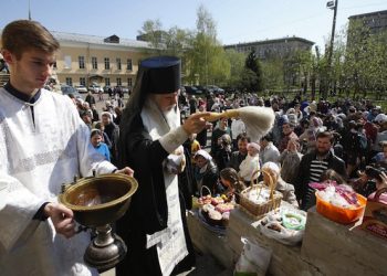 epa05283862 Russian Orthodox Church bishop Panteleimon (C) sprinkles Holy water to bless Easter cakes and eggs in front of a church in Moscow, Russia, 30 April 2016. Easter is the main religious celebration for Russian Orthodox Christians and will be celebrated this year on 01 May according to the Julian calender.  EPA/SERGEI CHIRIKOV