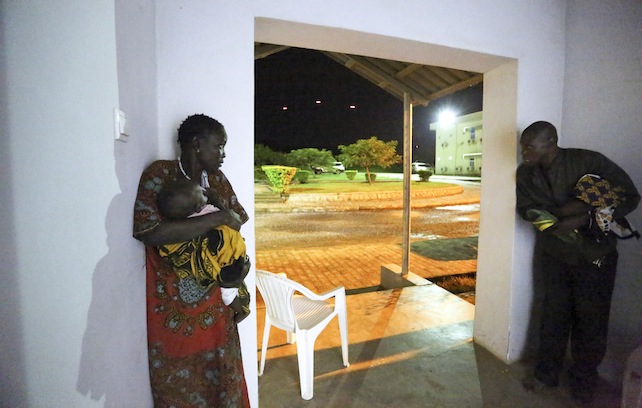 In this photo taken late Friday, July 8, 2016 and released by the United Nations Mission in South Sudan (UNMISS),  taking cover in the doorway of the UN offices as the fighting kicks off, tracers flying by in the background, the fighting was directly on the perimeter of the UN base the UN compound in the capital Juba, South Sudan. The president of South Sudan and his opposition rival both called Monday for a cease-fire in a conflict that has seen fierce clashes between their forces spread from the capital to a southeastern town. (Eric Kanalstein/UNMISS via AP)