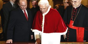 Pope Benedict XVI looks at a gift presented him by Russia's President Vladimir Putin at the Vatican Tuesday, March 13, 2007. It was the highest-level Kremlin-Vatican talks in more than three years, a meeting expected to focus on ways of easing tensions between Catholics and Orthodox Christians and finding common ground on moral issues. The meeting - the first between Benedict and Putin - is part of a visit that takes the Russian leader to Italy and Greece this week. At right is Cardinal Tarcisio Bertone, Vatican Secretary of State. (AP Photo/Andrew Medichini, Pool)
