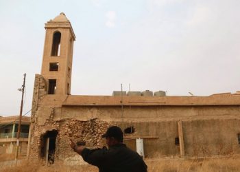 epa05601097 An Iraqi Army officer points to where a sniper fire heard was probably coming from, as he approaches a damaged church in the formerly IS held town of Bartila, some 27 km East of Mosul, Iraq, 24 October 2016. Iraqi officers told EPA on 24 October that the village of Khazna right after Bartila, as well as Mar Karamles and Hamdaniya have been liberated in the past 24 hours, but access to most of them was only possible with an Iraqi armored car as their streets have not been cleared of IEDs (Improvised Explosive Devices) yet. EPA reporters who were allowed in again into Bartila witnessed a sniper shots to which Iraqi forces responded with a mortar firing.  EPA/AMEL PAIN
