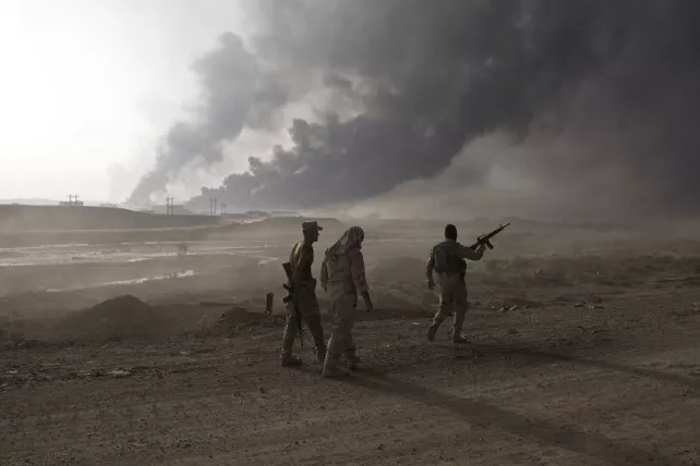 Iraqi army soldiers man a checkpoint as oil wells burn on the outskirts of Qayyarah, Iraq, Wednesday, Oct. 19, 2016. A senior Iraqi general on Wednesday called on Iraqis fighting for the Islamic State group in Mosul to surrender as a wide-scale operation to retake the militant-held city entered its third day. (AP Photo/Marko Drobnjakovic)