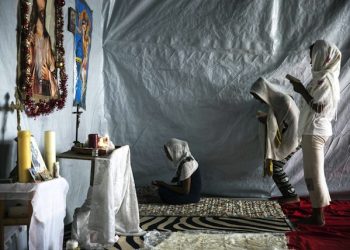 epa04875961 Three migrant women from Eritrea pray in a small church they have built at the makeshift migrant camp the 'Jungle' on the outskirts of Calais, France, 06 August 2015. More than 3,000 migrants live in the camp according to associations and non-governmental organizations (NGOs).  EPA/ETIENNE LAURENT