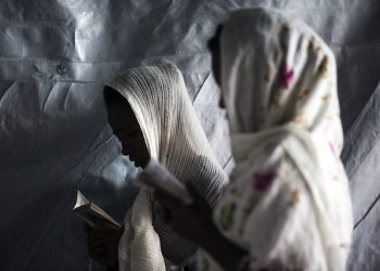 epaselect epa04875963 Two migrant women from Eritrea pray in a small church they have built at the makeshift migrant camp the 'Jungle' on the outskirts of Calais, France, 06 August 2015. More than 3,000 migrants live in the camp according to associations and non-governmental organizations (NGOs).  EPA/ETIENNE LAURENT