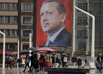 In this Tuesday, March 14, 2017 photo, people walk in central Istanbul's Taksim Square, backdropped by a poster of Turkish President Recep Tayyip Erdogan. The entire Turkish referendum campaign has been biased and unfair, those opposed to expanding the president’s powers say, noting they have been hampered by a lack of TV airtime, threats, violence, arbitrary detentions and even sabotage. Those reports come even as Erdogan himself has slammed European countries for not letting his ministers campaign on their soil for the April 16 vote on expanding his powers. (AP Photo/Lefteris Pitarakis)