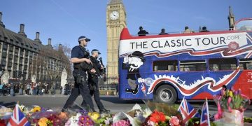epa05868002 Armed police walk past flowers in the  Parliament Square near to the scene of 22 March terror attack in central London, Britain, 24 March 2017. Scotland Yard said on 24 March 2017 that police have made nine arrests in relation to the terror attack in the Westminster Palace grounds and on Westminster Bridge on 22 March 2017 leaving at least five people dead, including the attacker, and 29 people injured.  EPA/HANNAH MCKAY