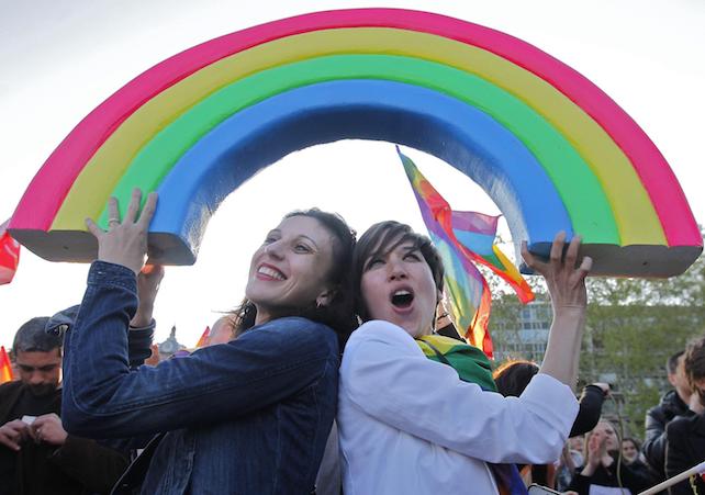 epa03674414 Two young women pose underneath a plastic rainbow sign during a demonstration in Montpellier, southern France, 23 April 2013, to celebrate the vote in the French National Assembly which legalizes gay marriage and allows same-sex couples to adopt children. The legalization makes France to become the 14th country in the world to legalize same-sex marriage, a major social reform since France banned the death penalty in 1981.  EPA/GUILLAUME HORCAJUELO