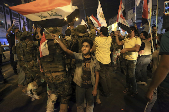 Iraqi security and civilians celebrate while holding national flags as they wait for the final announcement of the defeat of the Islamic state militants, in Basra, 340 miles (550 kilometers) southeast of Baghdad, Iraq, Sunday, July 9, 2017. Backed by the U.S.-led coalition, Iraq launched the operation to retake Mosul from Islamic State militants in October. (AP Photo/Nabil al-Jurani)