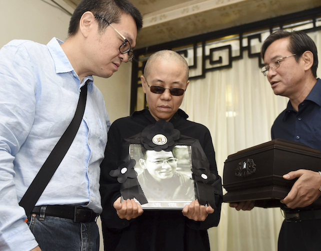 In this photo provided by the Shenyang Municipal Information Office, Liu Xia, center, wife of jailed Nobel Peace Prize winner and Chinese dissident Liu Xiaobo, holds a portrait of him during his funeral at a funeral parlor in Shenyang in northeastern China's Liaoning Province, Saturday, July 15, 2017. China says the body of Liu Xiaobo, who died this week after a battle with liver cancer, has been cremated. The government of the city of Shenyang in northeastern China, where Liu was treated, said in a briefing that the cremation took place Saturday morning in a ceremony attended by family and friends. (Shenyang Municipal Information Office via AP)