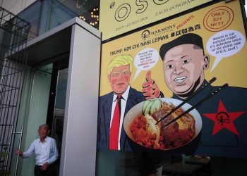 epa06788443 A man exits a door next to a poster depicting US President Donald J. Trump (C), North Korean leader Kim Jong-Un (R), and a promotional dish of 'Trump-Kim Chi Nasi Lemak' at a restaurant in Singapore, 06 June 2018. The White House has confiremd that US President Donald J. Trump and North Korean leader Kim Jong-un will meet at the Capella Hotel for their expected historic summit on 12 June 2018.  EPA/WALLACE WOON