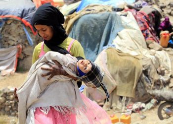 epa06971934 A displaced Yemeni girl holds her infant sister outside temporary shelters at a camp for Internally Displaced Persons (IDPs) on the outskirts of Sana'a, Yemen, 25 August 2018. According to reports, the United Nations has called for an impartial and prompt probe into attacks targeting civilians in war-torn Yemen after alleged Saudi-led airstrikes hit a truck allegedly carrying displaced people in the western Yemeni province of Hodeidah, killing at least 22 children and four women.  EPA/YAHYA ARHAB