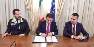 Il premier Giuseppe Conte firma il decreto sicurezza tra i due vice Matteo Salvini e Luigi Di Maio