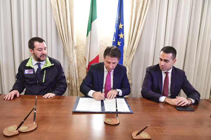 Il premier Giuseppe Conte firma il decreto sicurezza tra i due vice Matteo Salvini e Luigi Di Maio