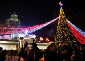 epa05687539 Chinese people take selfie photos near by a Christmas tree outside the state-approved Xuanwumen Catholic Church, otherwise known as the South Cathedral in Beijing, China 24 December 2016. Christians in China attend church masses as they prepare to celebrate the religious holiday to commemorate the birth of Christ.  EPA/WU HONG