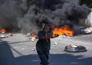 epa07176026 A child covers his head during protest, in Port-au-Prince, Haiti, 18 November 2018. Thousands of Haitians took the streets in a new national protest against corruption and impunity which has left at least two dead and several wounded.  EPA/ESTAILOVE ST-VAL