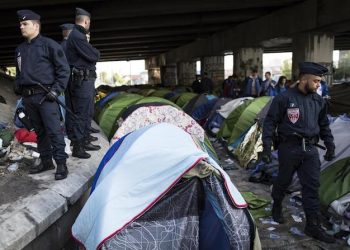 epa06772488 Police form a cordon at a large makeshift migrant camp along the Canal Saint Denis, in northern Paris, France, 30 May 2018. The camp, dubbed 'Millenaire' after the nearby shopping center, and home to an estimated 1,700 migrants, was peacefully cleared in a police operation which began at daybreak. The migrants boarded buses and will be relocated to shelters around the Paris area.  EPA/IAN LANGSDON