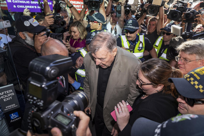 Il cardinale George Pell tra fotografi e polizia all'ingresso del tribunale di Melbourne