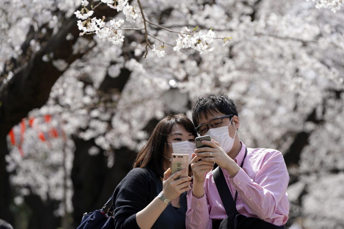 Coppia con protezione anti coronavirus davanti allo smartphone